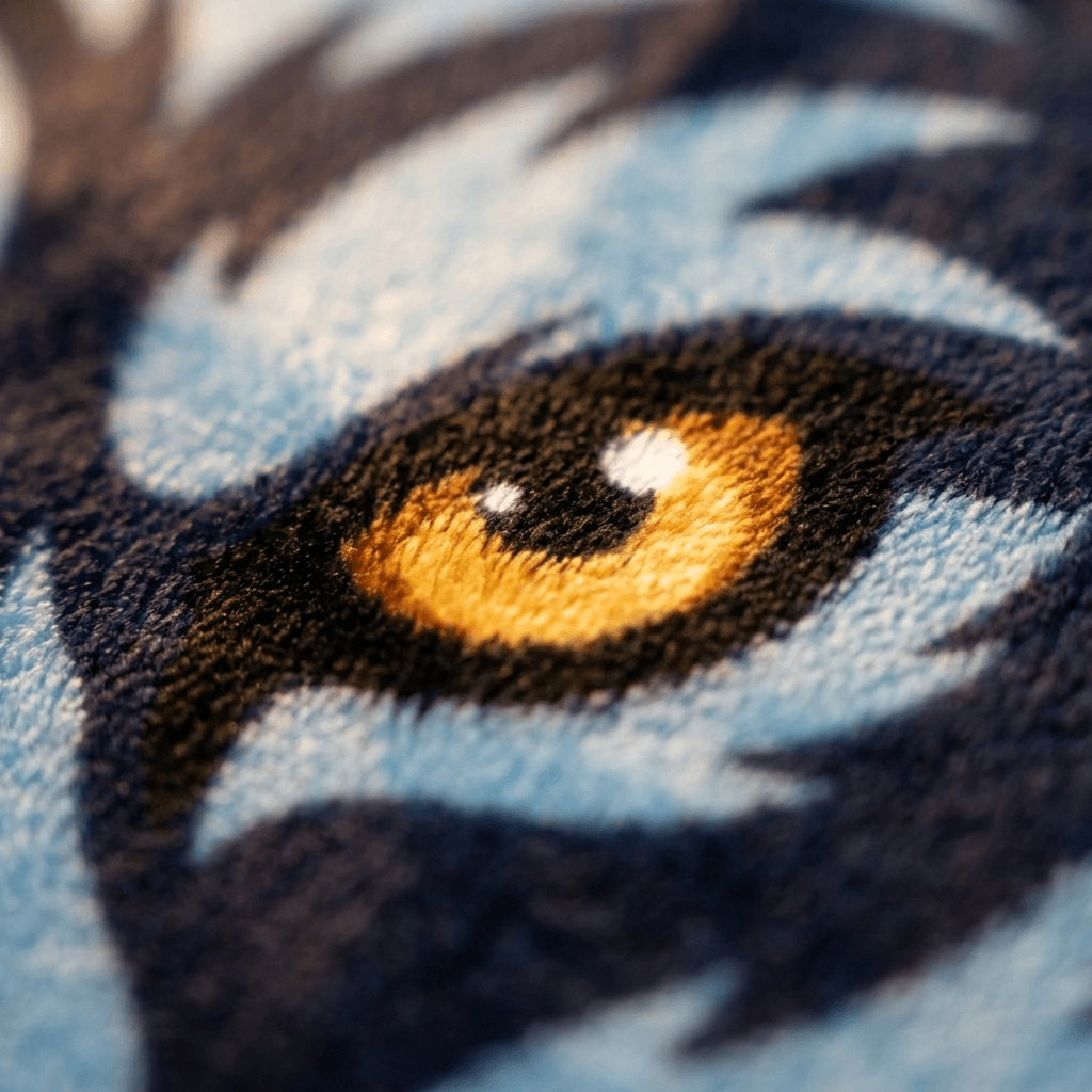 Extreme close-up of a mascot's amber eye printed on plush NubaySoft fabric, showing individual fiber-level detail